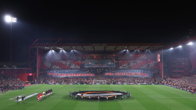 Football stadium at night with players on the pitch and a large banner reading FOR A NEW GENERATION OUR TIME HAS COME