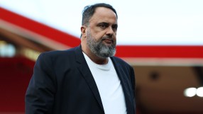 Evangelos Marinakis, owner of Nottingham Forest, in a dark jacket and white shirt, looking serious at a stadium.