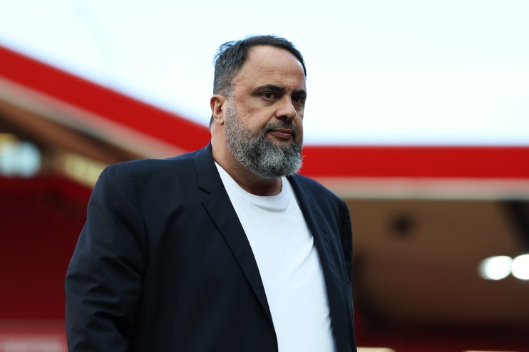 Evangelos Marinakis, owner of Nottingham Forest, in a dark jacket and white shirt, looking serious at a stadium.