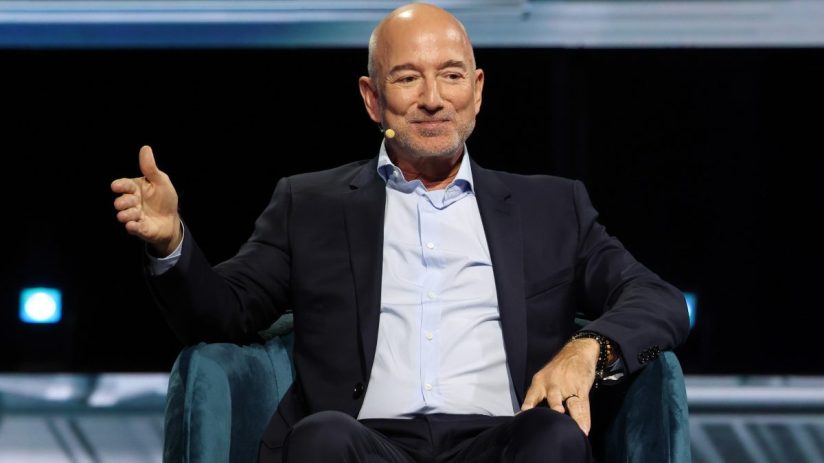 Jeff Bezos, Amazon founder, in a blue suit and light shirt, speaking at a business event