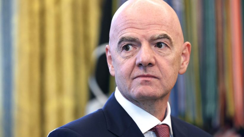 Gianni Infantino, FIFA President, in a dark suit and red tie, looking right with a serious expression.