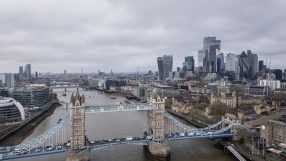 Aerial view of Tower Bridge, Thames River, and London skyline with skyscrapers on a cloudy day