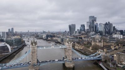 Aerial view of Tower Bridge, Thames River, and London skyline with skyscrapers on a cloudy day