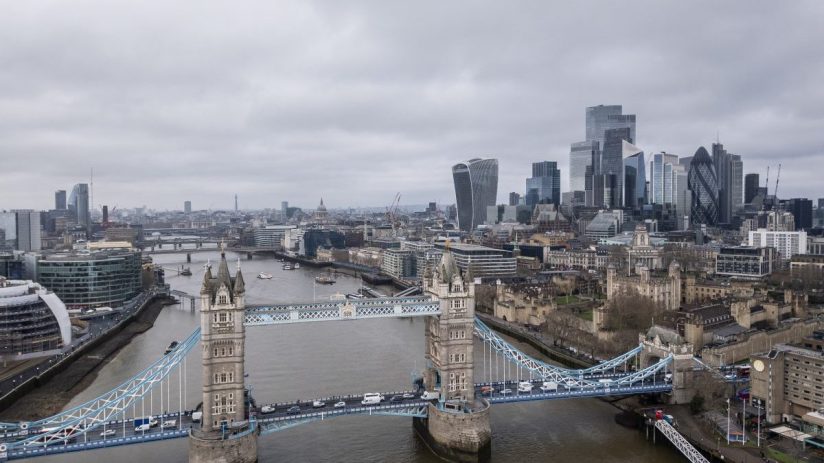 Aerial view of Tower Bridge, Thames River, and London skyline with skyscrapers on a cloudy day