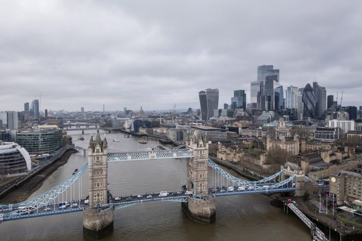 Aerial view of Tower Bridge, Thames River, and London skyline with skyscrapers on a cloudy day