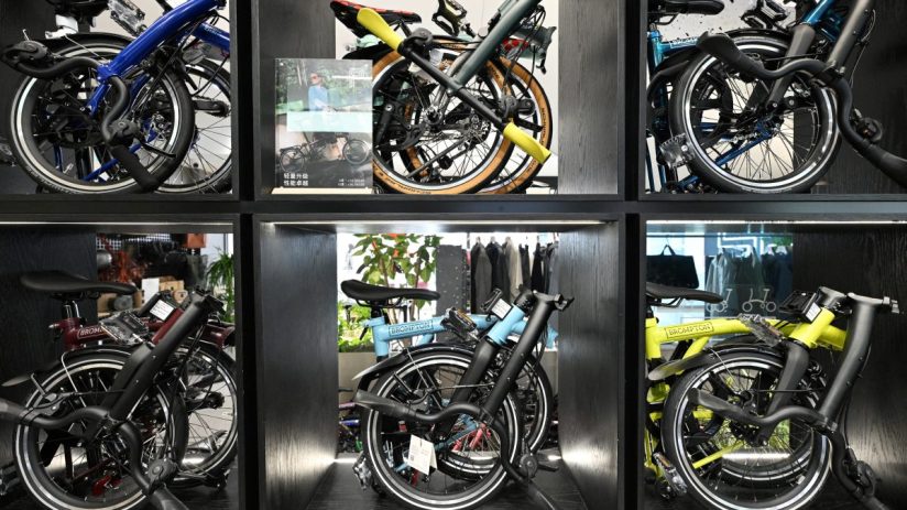 Six Brompton folding bicycles in various colors displayed in individual black cubbies.