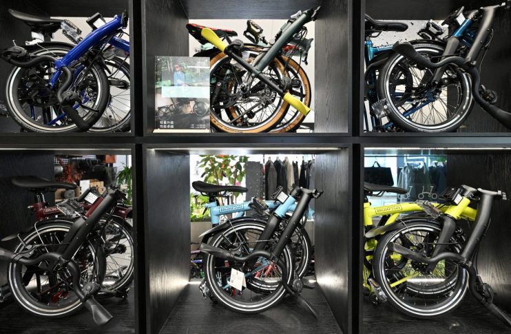 Six Brompton folding bicycles in various colors displayed in individual black cubbies.