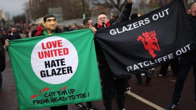 Football fans protest holding Love United Hate Glazer and Glazers Out Ratcliffe Out banners.