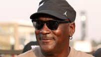 Michael Jordan smiling, wearing sunglasses and a black cap with a white Jumpman logo.