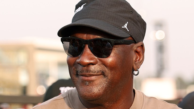 Michael Jordan smiling, wearing sunglasses and a black cap with a white Jumpman logo.