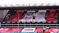 Empty stadium stands with large banners supporting MND awareness, Gloucester Rugby, and the Slater Cup.