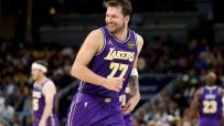 Luka Dončić in a purple Lakers jersey with number 77, smiling on a basketball court