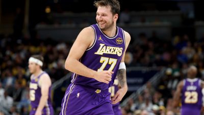 Luka Dončić in a purple Lakers jersey with number 77, smiling on a basketball court
