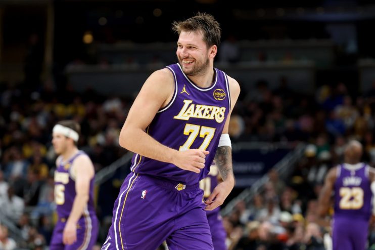Luka Dončić in a purple Lakers jersey with number 77, smiling on a basketball court