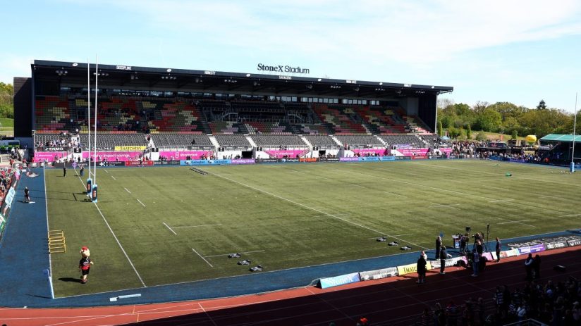 StoneX Stadium, home of Saracens Rugby Club, with empty seats in the stands and a clear green field.