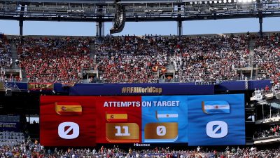 Large stadium scoreboard displaying Attempts on Target for Spain (11) and Argentina (0) with cheering fans.