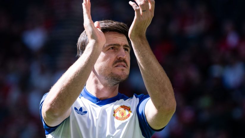 Harry Maguire in a Manchester United jersey, clapping during a match, looking up.