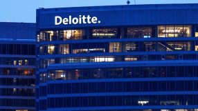 Deloitte building exterior at dusk with illuminated offices and company logo visible