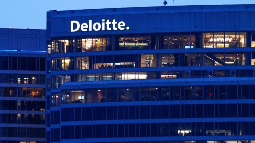 Deloitte building exterior at dusk with illuminated offices and company logo visible