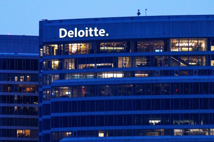 Deloitte building exterior at dusk with illuminated offices and company logo visible