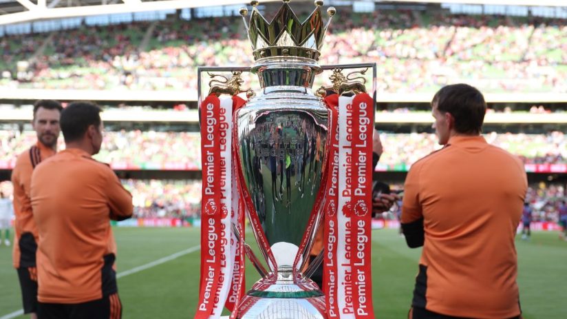 Premier League trophy on display at a stadium with spectators in the background