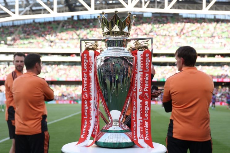 Premier League trophy on display at a stadium with spectators in the background