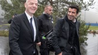 Gianni Infantino and Lu&iacute;s Figo smiling, walking outdoors with security, on a wet day.