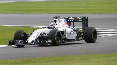 White Martini Racing Formula 1 car on a grey track with green grass borders, in motion during a race.