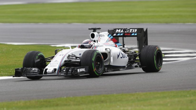 White Martini Racing Formula 1 car on a grey track with green grass borders, in motion during a race.