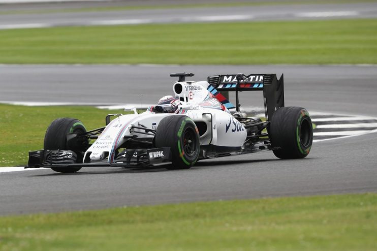 White Martini Racing Formula 1 car on a grey track with green grass borders, in motion during a race.