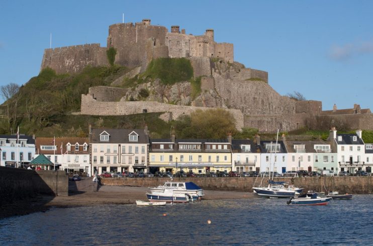Mont Orgueil Castle overlooking Gorey Harbour with boats and waterfront buildings in Jersey, Channel Islands.
