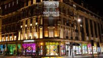 Harvey Nichols department store at night, illuminated with neon signs and colorful window displays.
