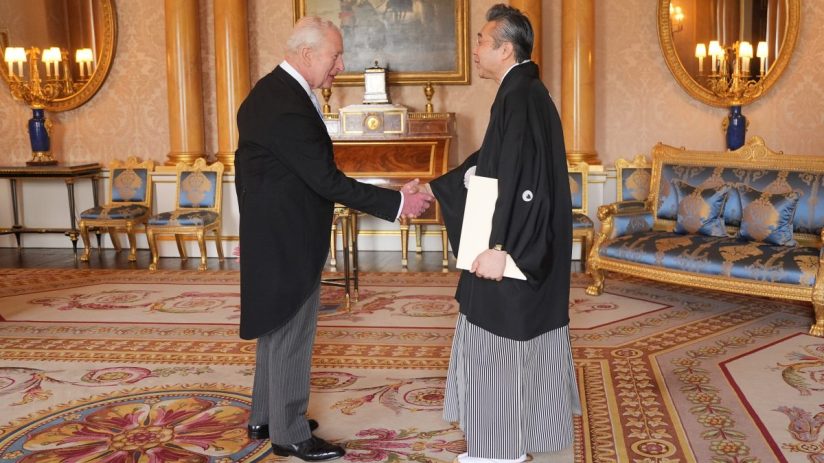 King Charles III and Hiroshi Suzuki shaking hands in a richly decorated room
