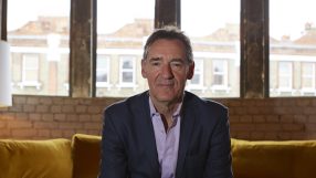 Jim ONeill, economist and former Goldman Sachs chairman, sitting on a yellow sofa in front of large windows.