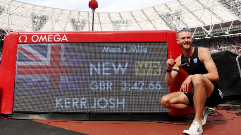 Josh Kerr celebrates new mile record 3:42.66 on Omega scoreboard, Union Jack visible, track stadium background.