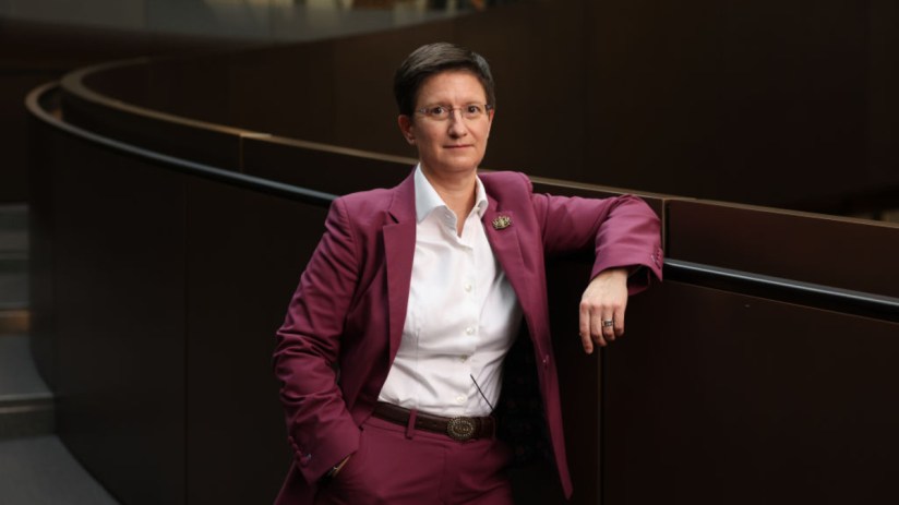 Julia Hoggett, London Stock Exchange CEO, in a magenta suit leaning on a dark railing.