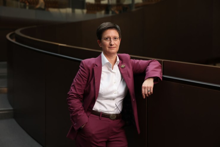 Julia Hoggett, London Stock Exchange CEO, in a magenta suit leaning on a dark railing.