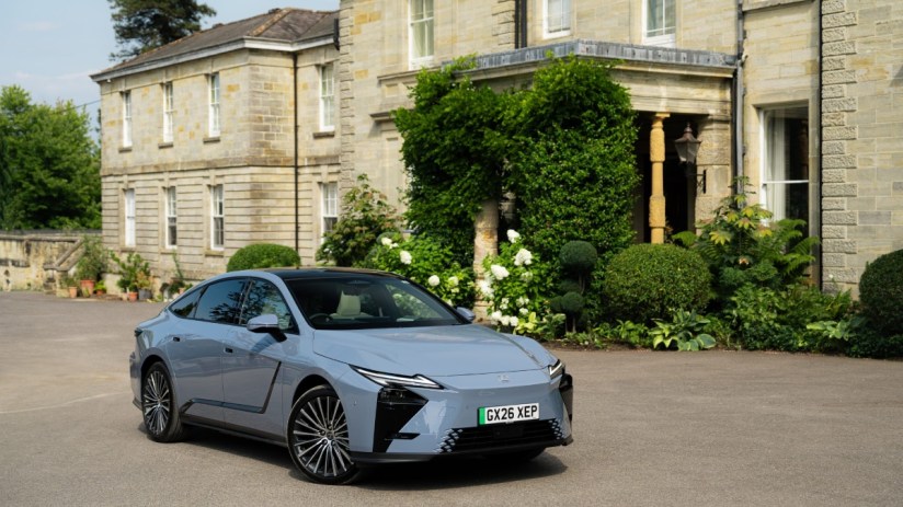 Lexus ES350e electric car in light blue, parked on a paved driveway in front of a stone building.