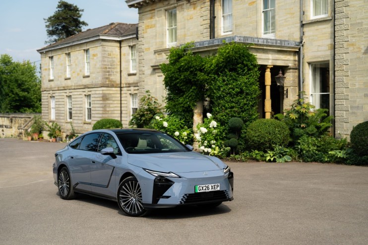 Lexus ES350e electric car in light blue, parked on a paved driveway in front of a stone building.