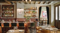 Lita restaurant interior with bar, bottles, shelves, and dining tables set with glasses and plates.
