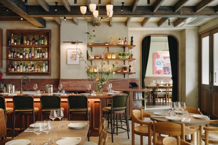 Lita restaurant interior with bar, bottles, shelves, and dining tables set with glasses and plates.