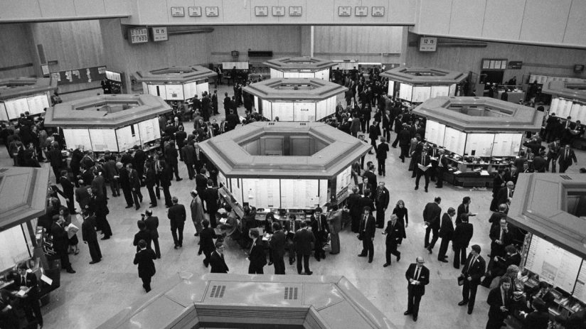 Busy London Stock Exchange trading floor in the 1980s with brokers at hexagonal trading posts.