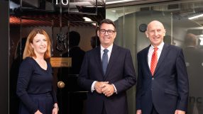 Louise Haigh, Andy Burnham, and another man smiling in front of a dark door with 10 visible.