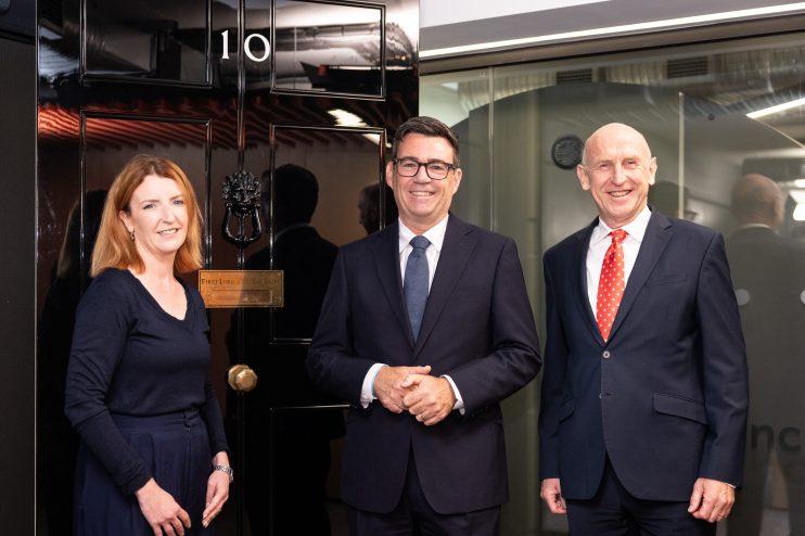 Louise Haigh, Andy Burnham, and another man smiling in front of a dark door with 10 visible.