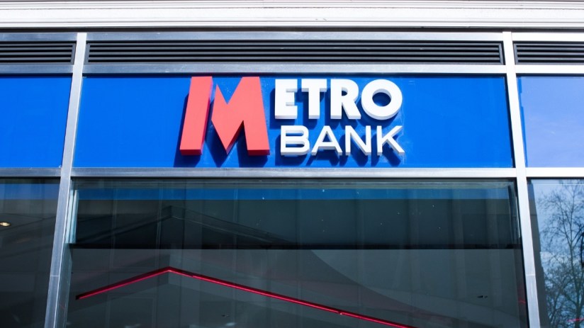 Metro Bank logo on a blue sign above a modern building entrance with reflective windows