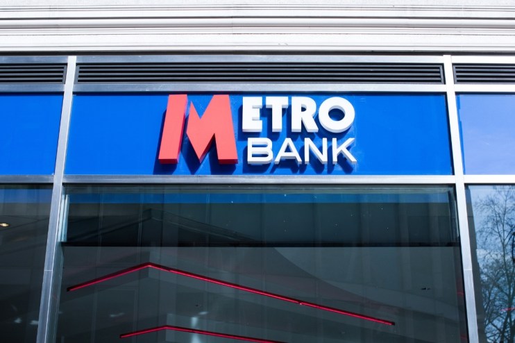 Metro Bank logo on a blue sign above a modern building entrance with reflective windows