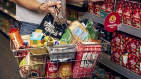 Shopper holding a basket filled with Morrisons groceries, including tortilla chips, bread, and flour, next to an Unbeatabl...