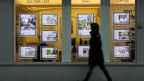 Person walks past a real estate agents window displaying properties for sale and to let.