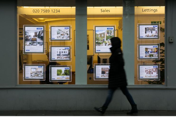 Person walks past a real estate agents window displaying properties for sale and to let.