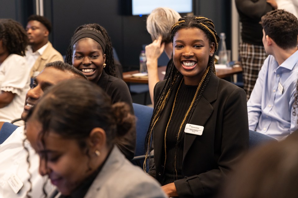 Hakima Onileere of Investec smiling at a business event, surrounded by other attendees.